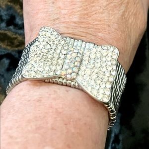 Silver metal stretchy bracelet with large rhinestone encrusted bow.